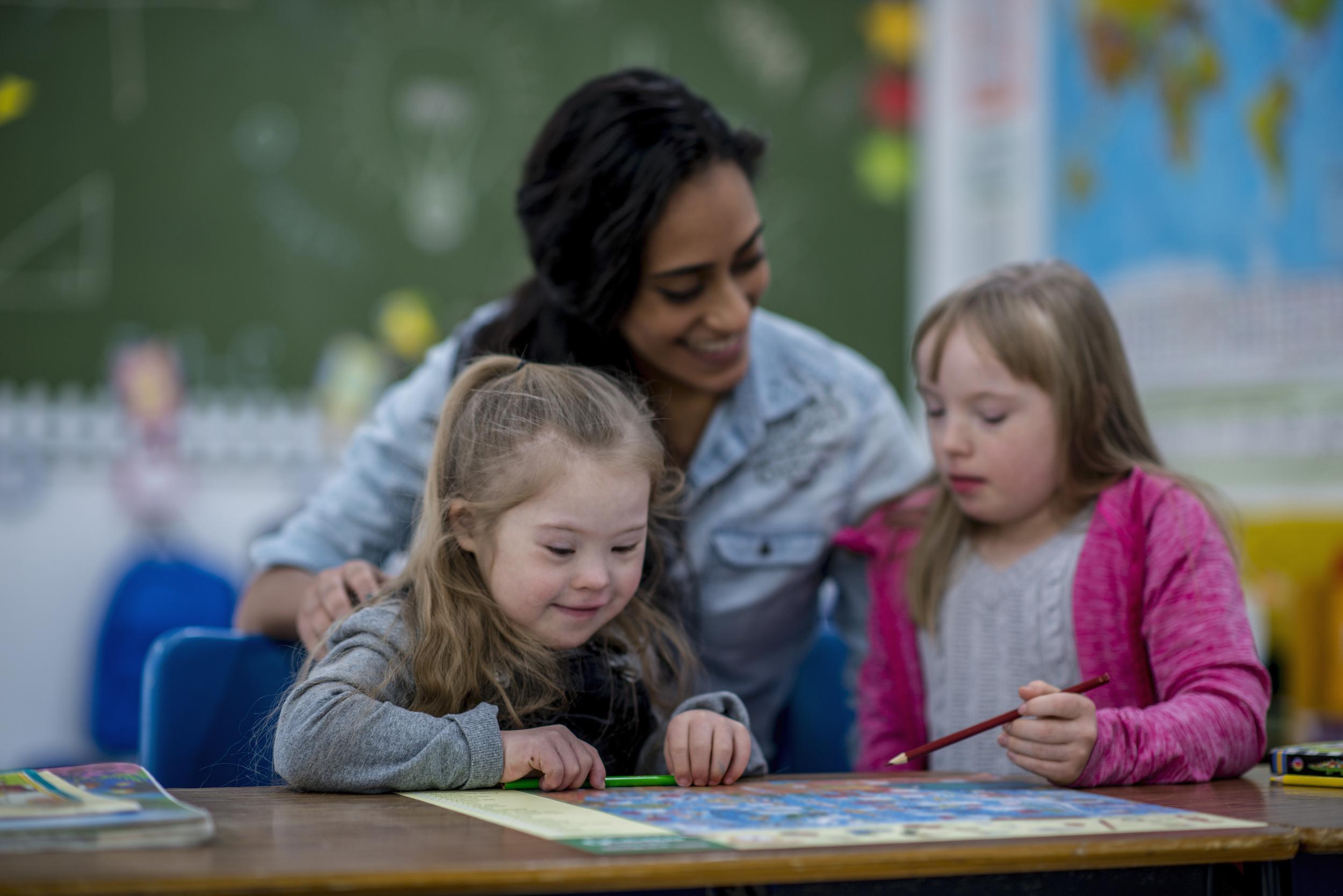 woman teacher helping two students with drawing