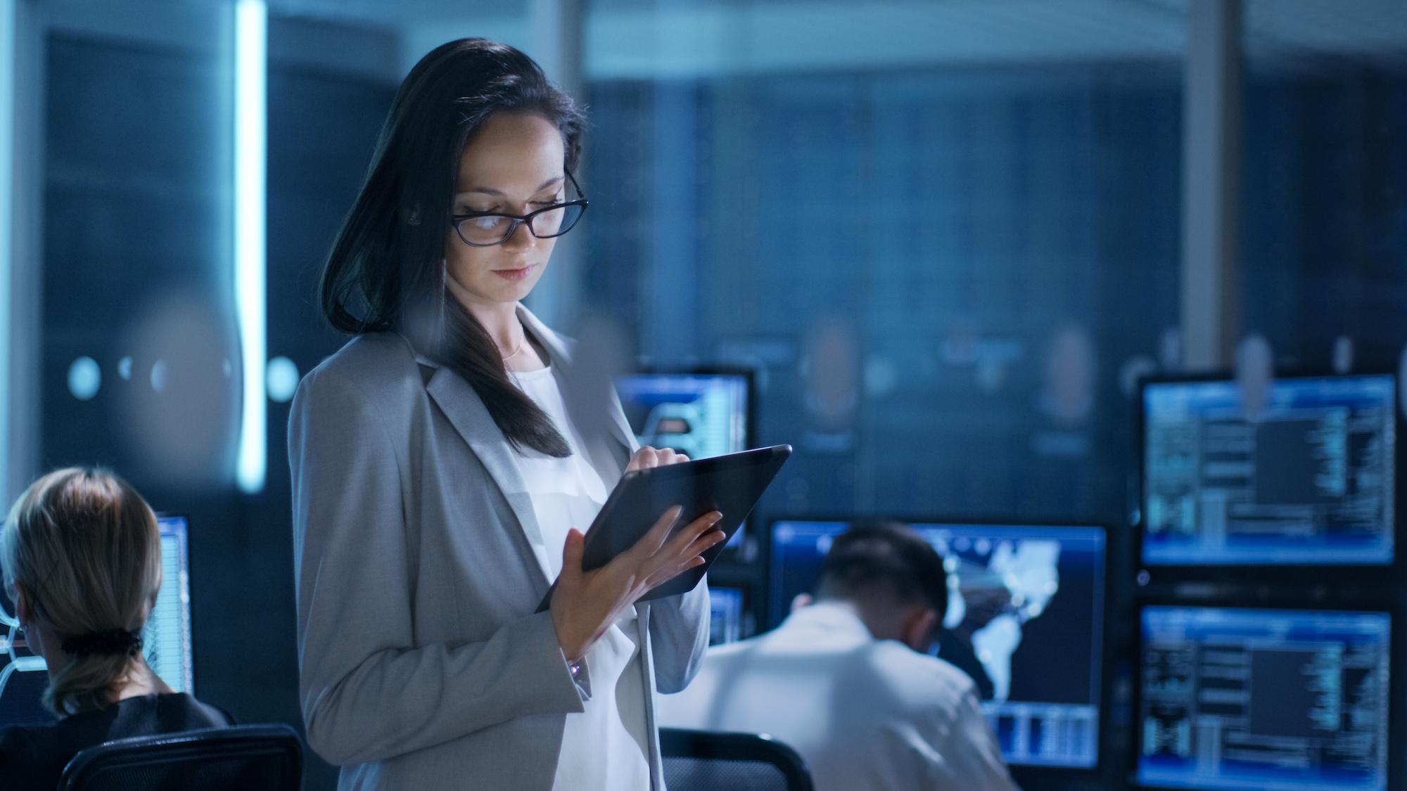 young female engineer uses tablet in system control cente