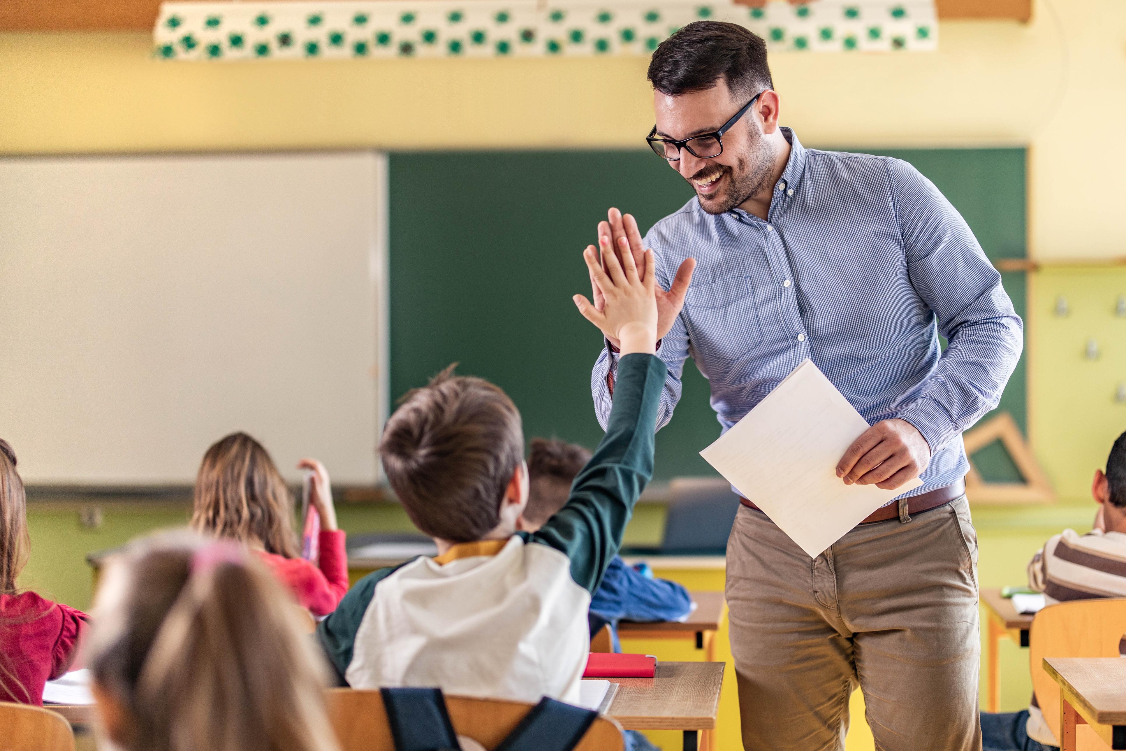 happy teacher and schoolboy giving each other high five